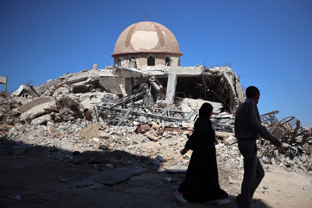 A couple walk past a destroyed mosque in Khan Younis.