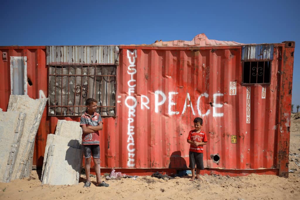 A family lives inside this shipping container. Someone has written 'peace' messages on the outside