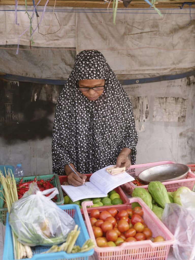 Adifa balancing her books after learning financial skills through the program.