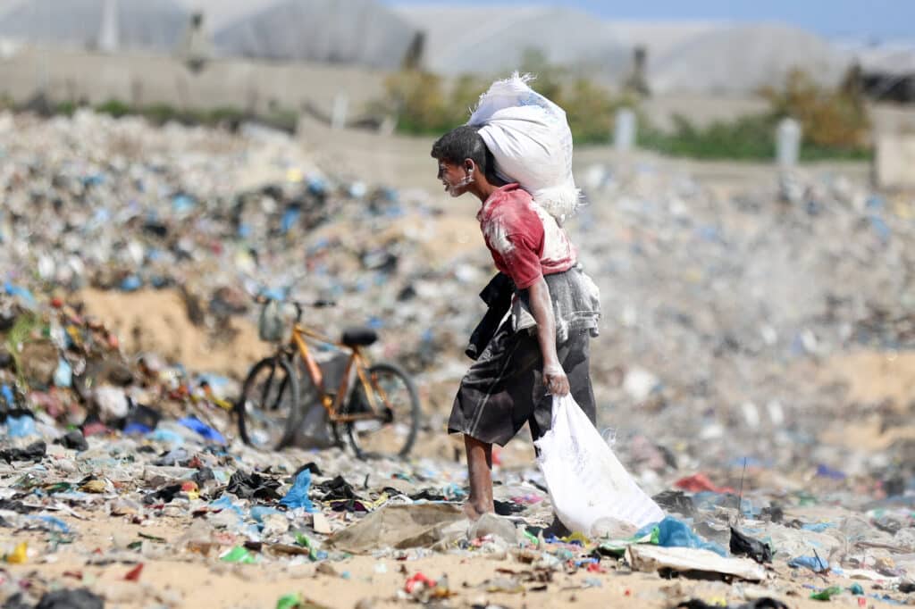 A young boy drags food through the ruins in Gaza